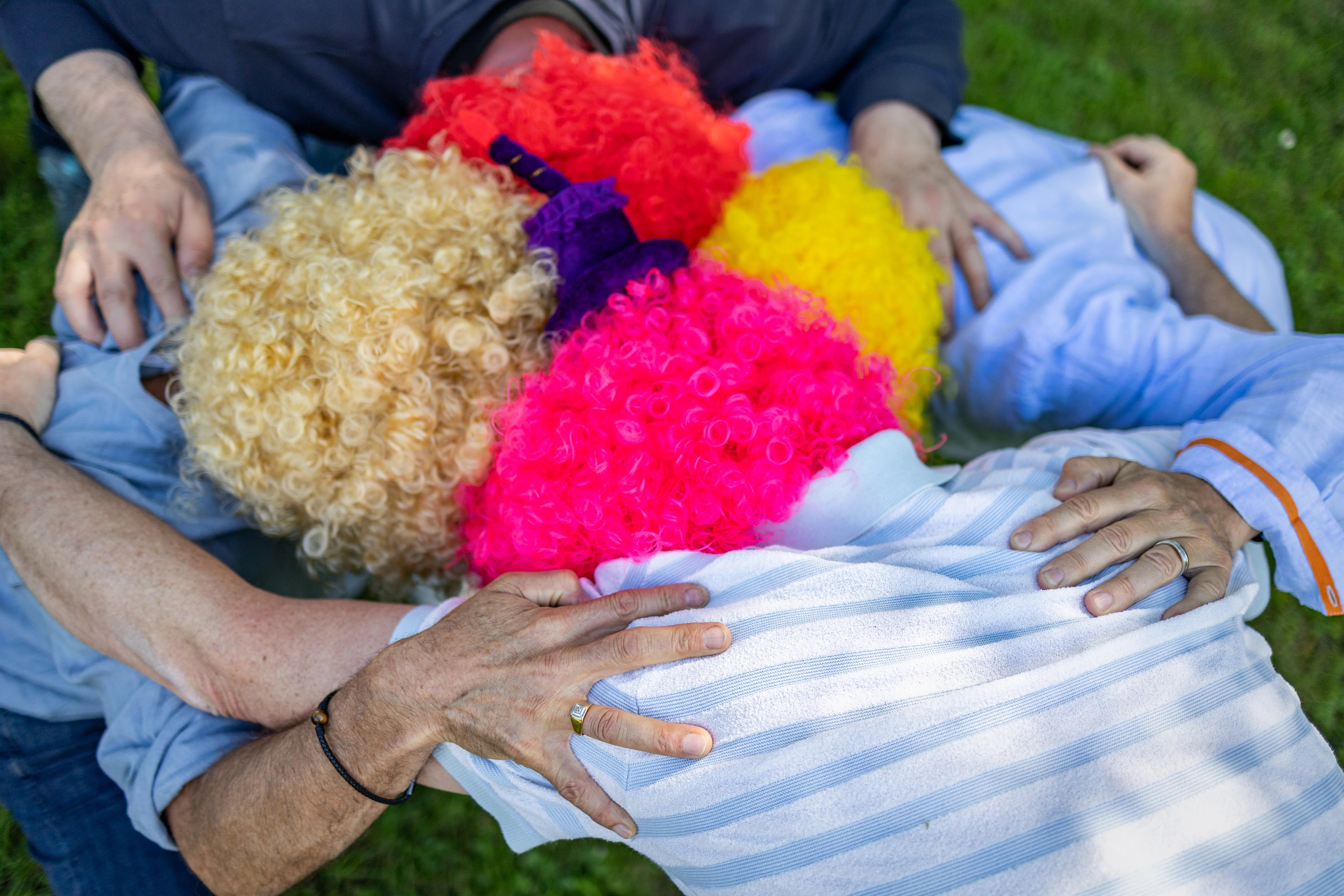 Groupe d'amis en cercle montrant leurs perruques lors d'une fête vers d'Annecy photographié par Marine Bourely Photographe