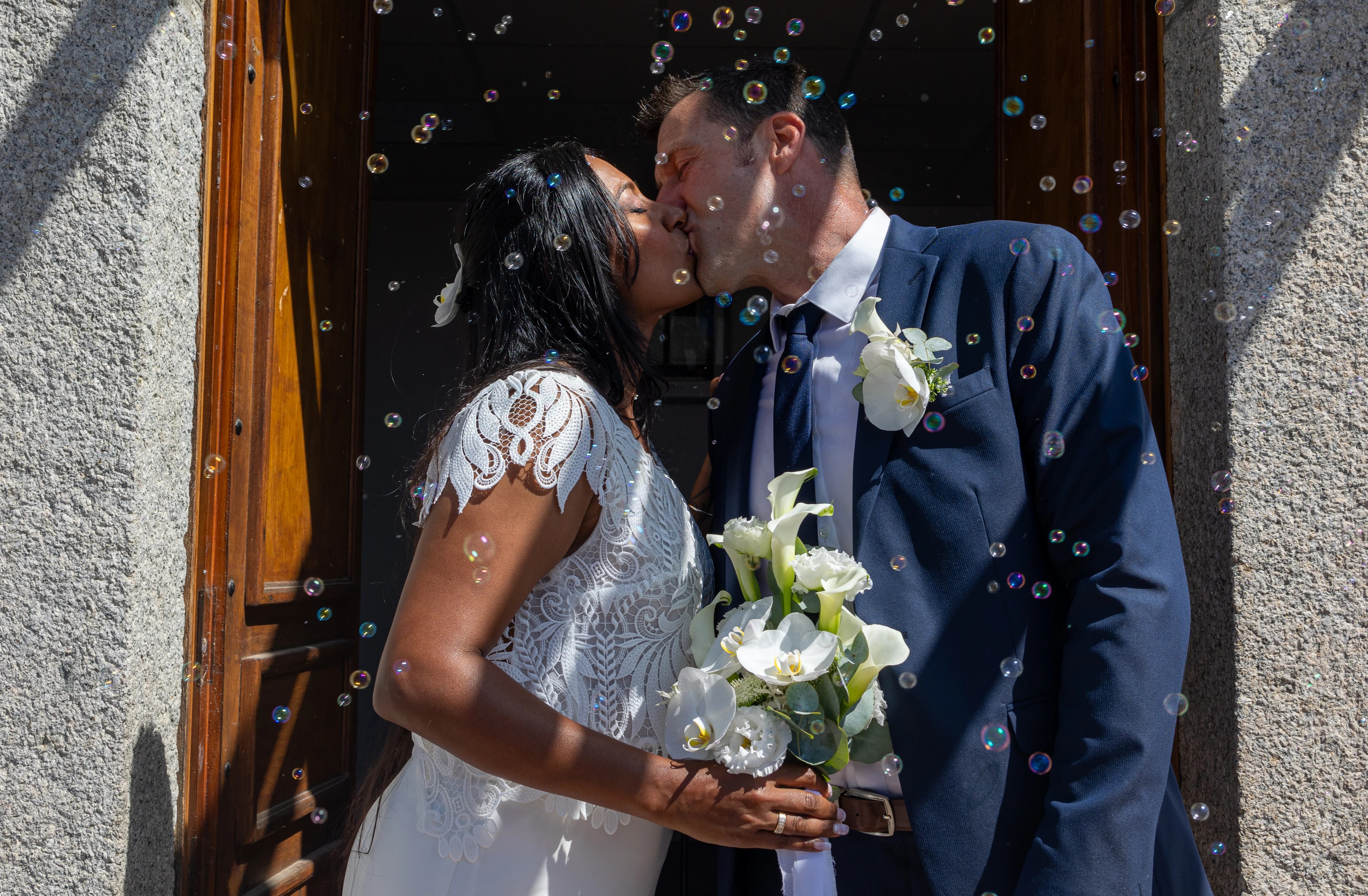 Mariés qui s'embrassent en sortie de mairie avec des bulles autour d'eux photographiés par Marine Bourely Photographe