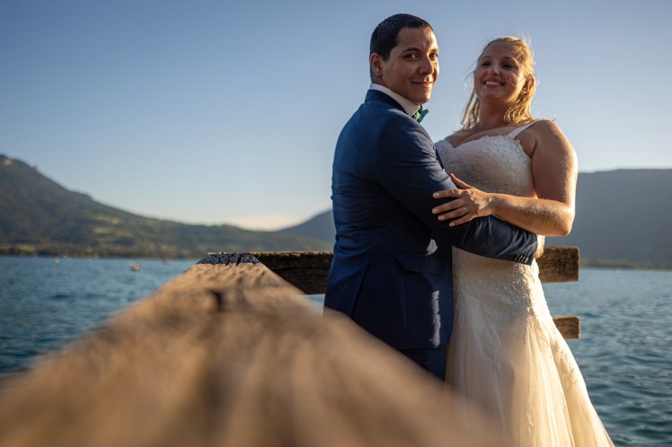 Mariés qui s'enlacent sur un ponton du lac d'Annecy pendant leur séance after day photographiés par Marine Bourely Photographe