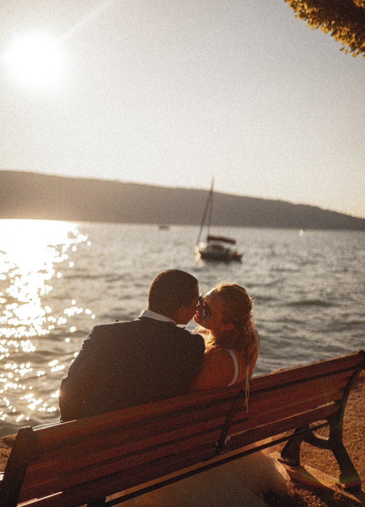 Mariés qui s'embrassent sur un banc face au lac d'Annecy pendant leur séance after day photographiés par Marine Bourely Photographe