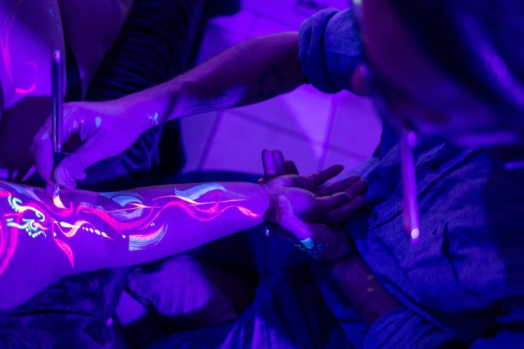 Odjin art de we are bodyful en train de peindre un bras bodypaint aux uv photographiée par Marine Bourely Photographe