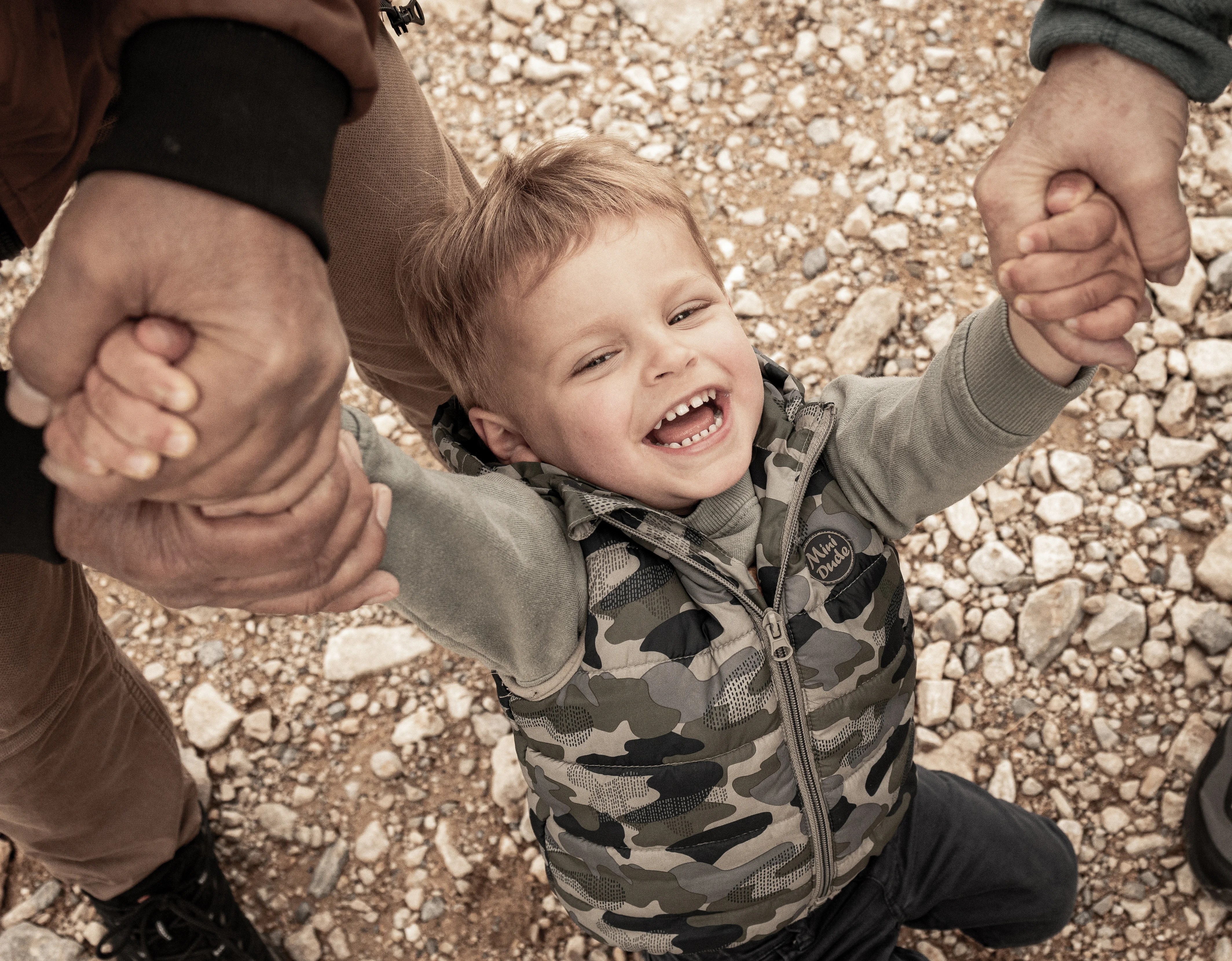 Petit garcon qui rit en tenant la main de ses parents photographié par Marine Bourely Photographe