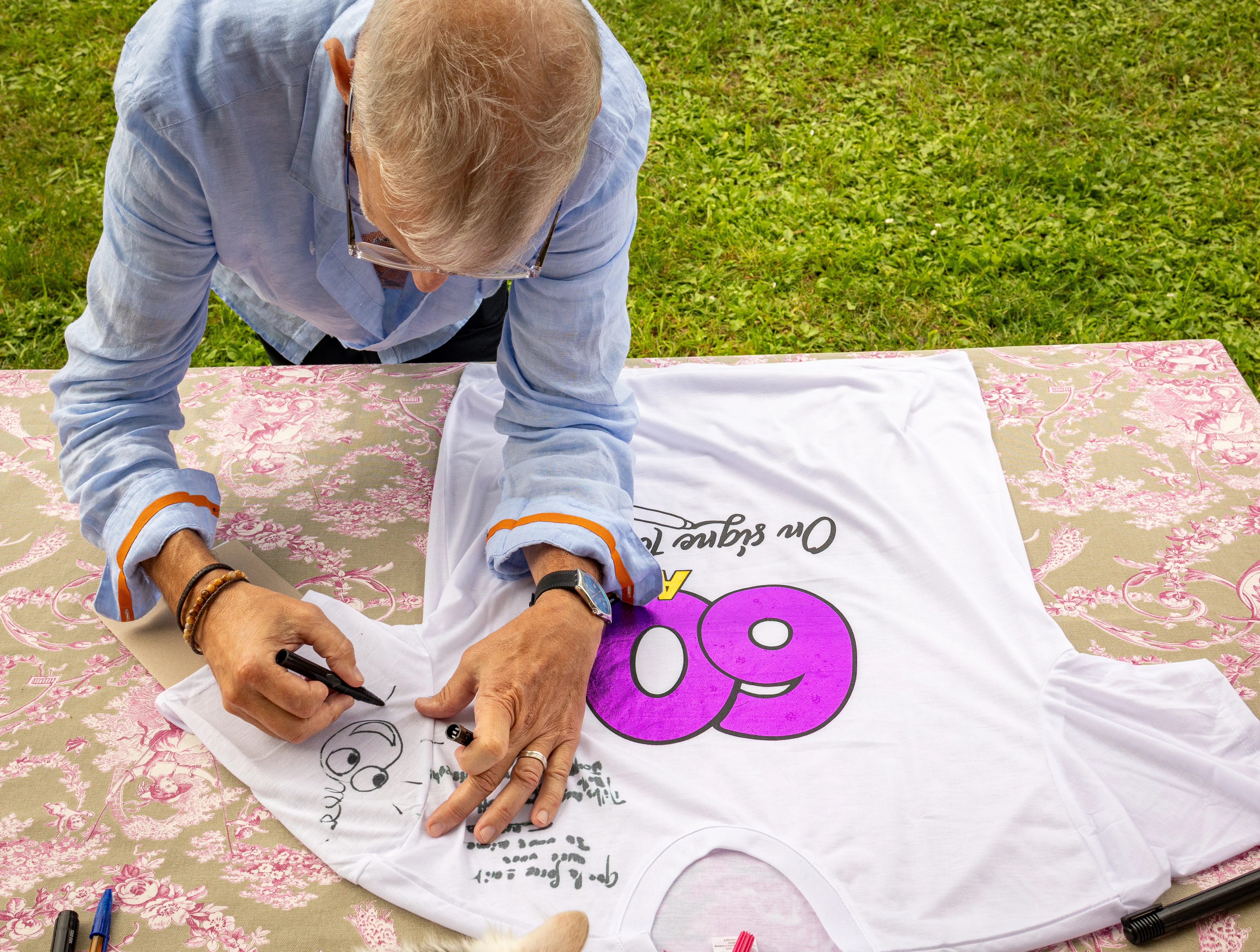 Homme signant un t-shirt pour un 60e anniversaire photographié par Marine Bourely Photographe