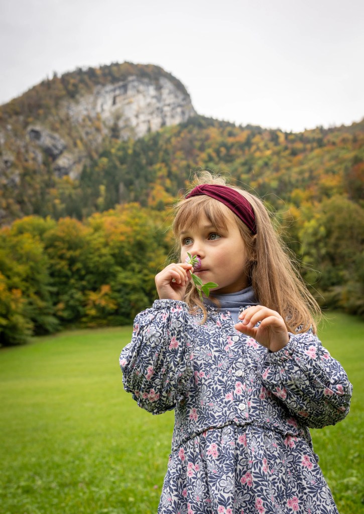Fillette qui sent une fleur en automne dans les Bauges photographiée par Marine Bourely Photographe