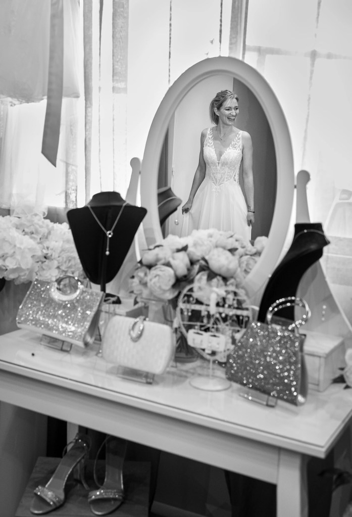 Future mariée essayant robe et bijoux devant un miroir photographiée par Marine Bourely Photographe