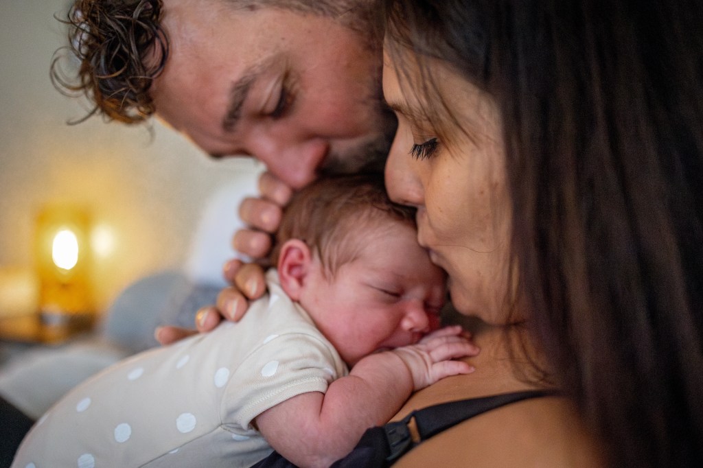 Couple qui embrasse son nouveau né endormi photographié par Marine Bourely Photographe