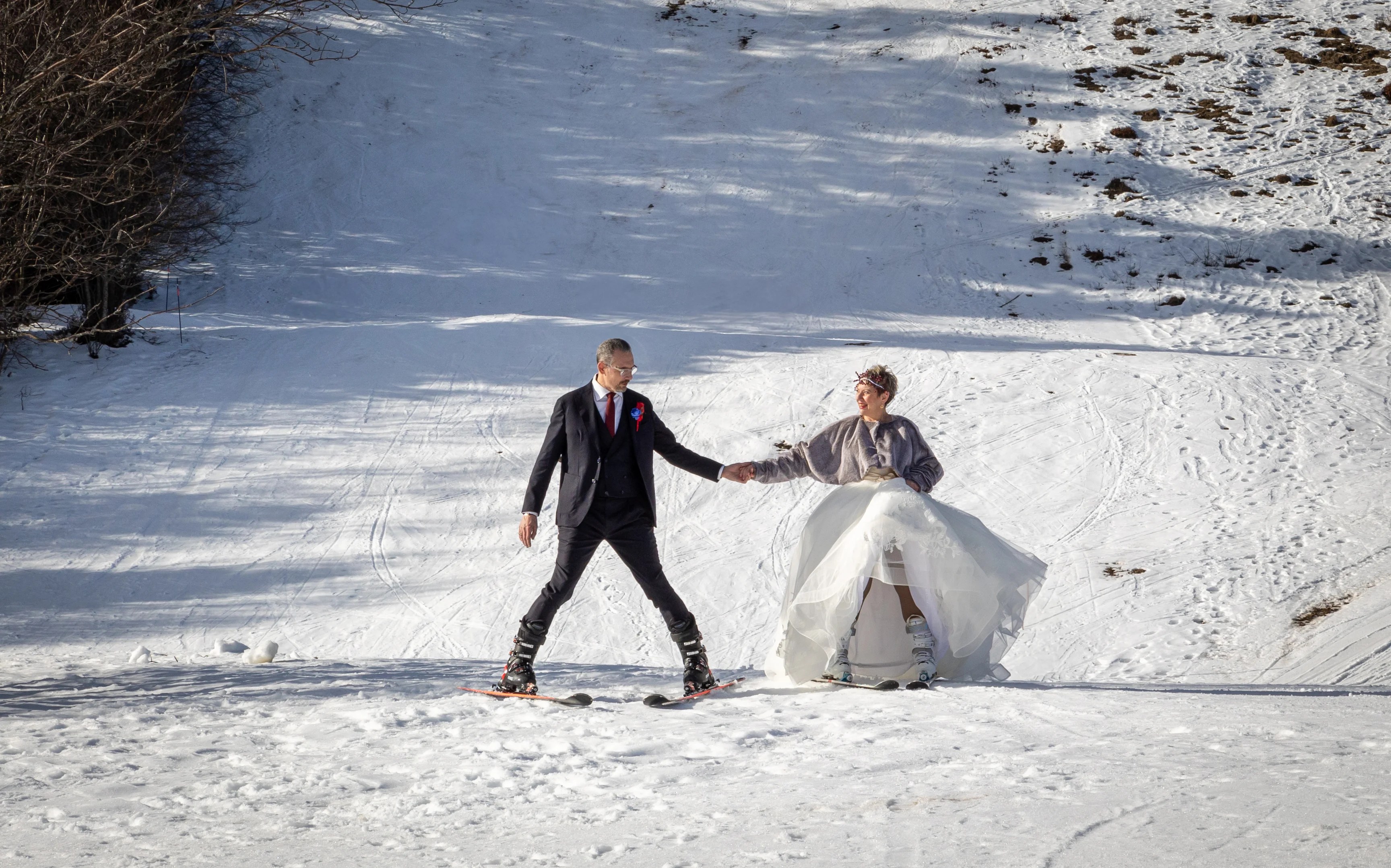 Mariés qui arrivent à la cérémonie en ski sur la piste la feclaz photographiés par Marine Bourely Photographe