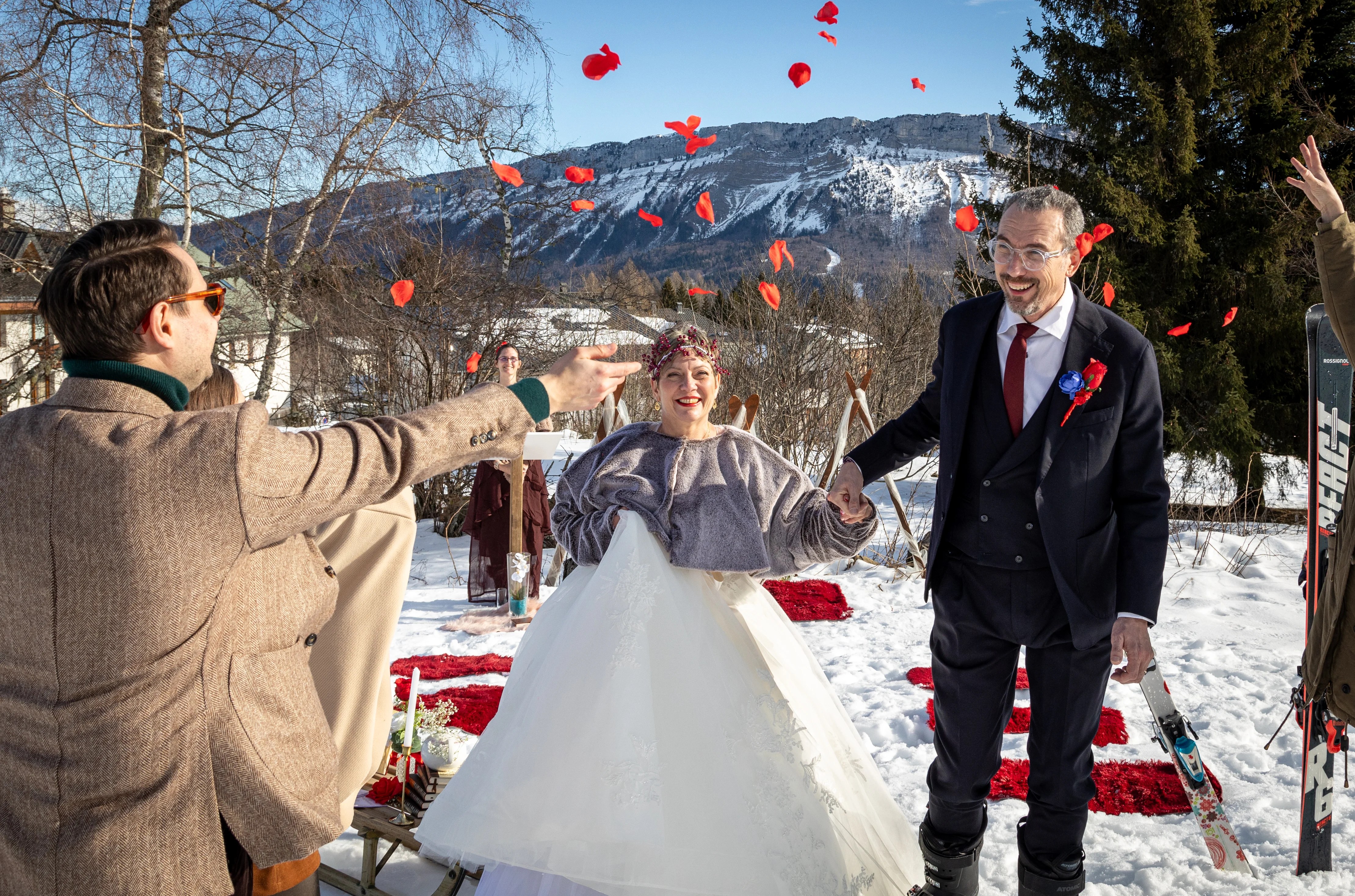 Mariés qui finissent la cérémonie laïque sous des pétales de rose à La Feclaz dans la neige photographiés par Marine Bourely Photographemarine bourely photographe annecy aix les bains rumilly chambéry chanaz