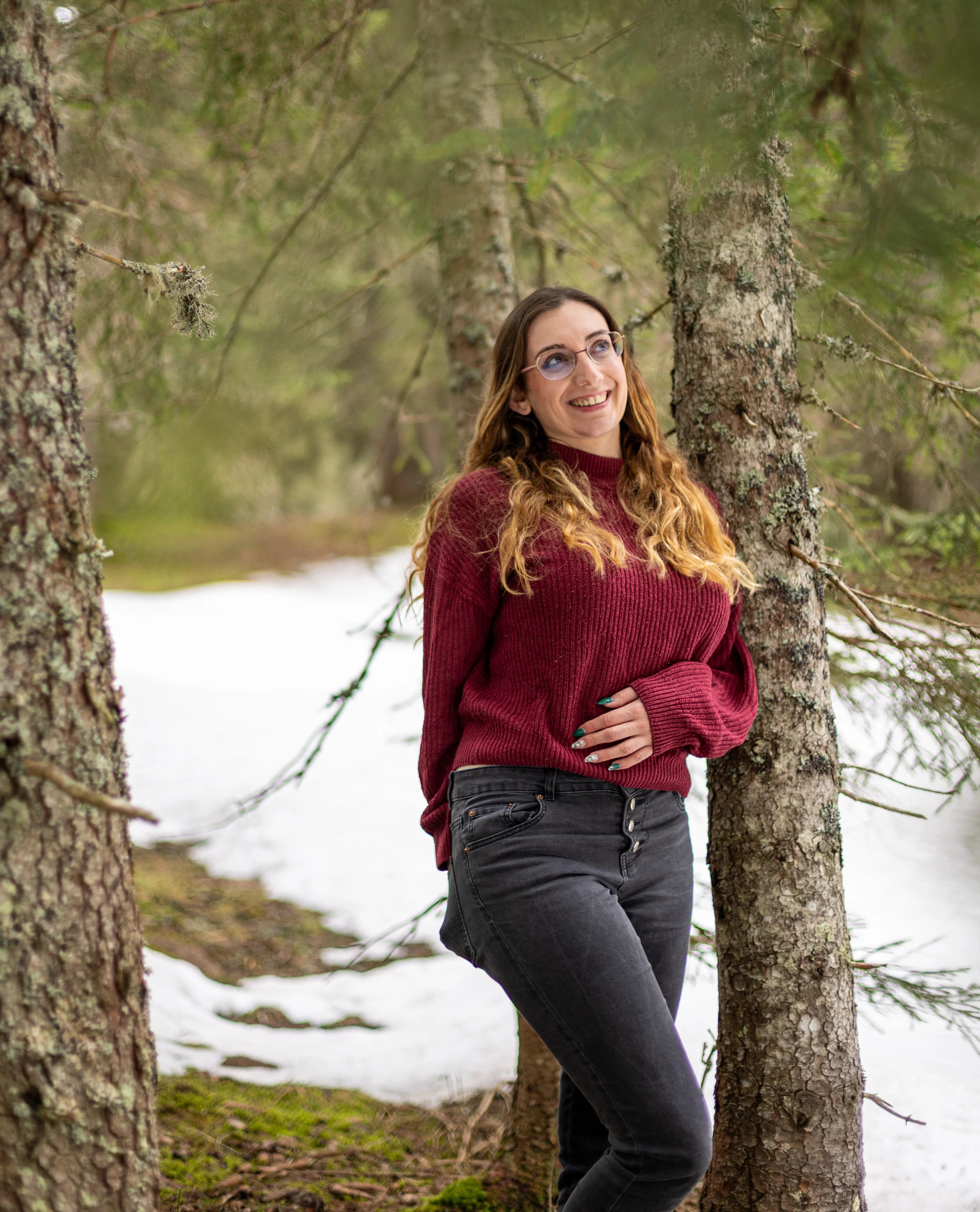 Femme souriante au milieu de sapins sur le plateau des Glières photographiée par Marine Bourely photographe