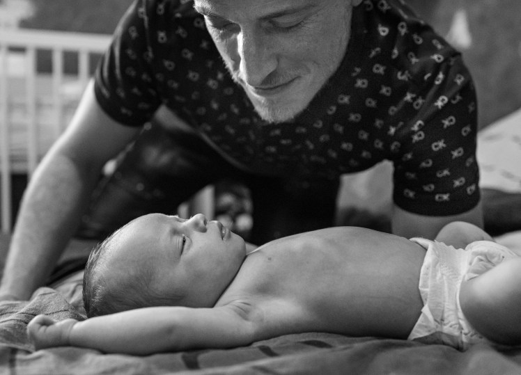 Papa qui se penche sur son bébé allongé à Saint Félix vers Annecy photographiés par Marine Bourely photographe