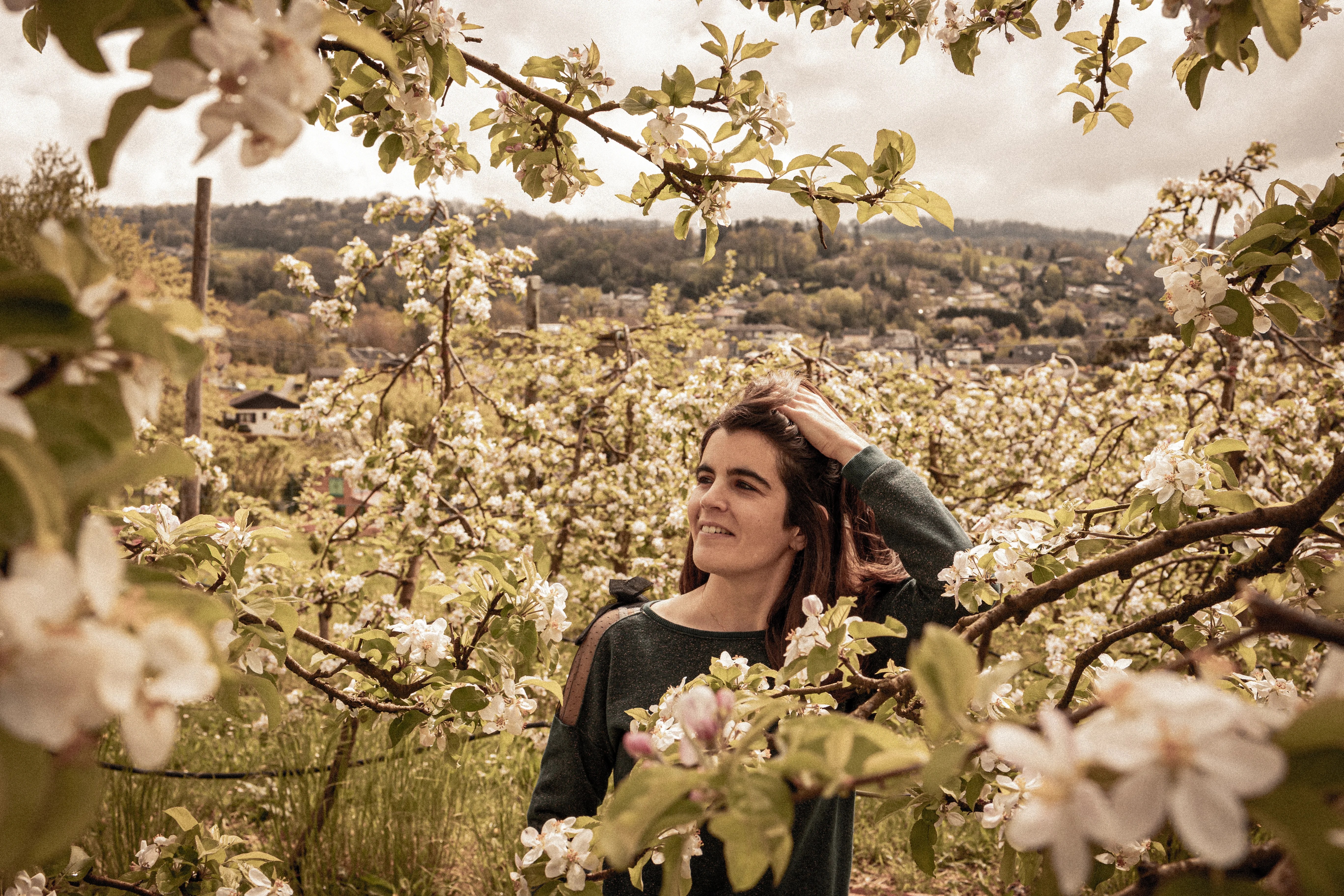 Jeune femme heureuse dans un champ de cerisiers en fleurs vers Annecy photographiée par Marine Bourely Photographe
